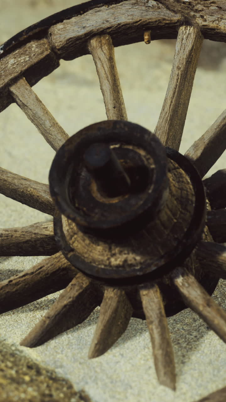 Ruota di carro in legno appoggiata su una spiaggia sabbiosa vicino a una pietra