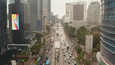 Aerial-dolly-retreating-low-flying-shot-of-vehicles-on-a-busy-multi-lane-highway-with-police-car-and-public-transportation-in-modern-city-center-of-Jakarta