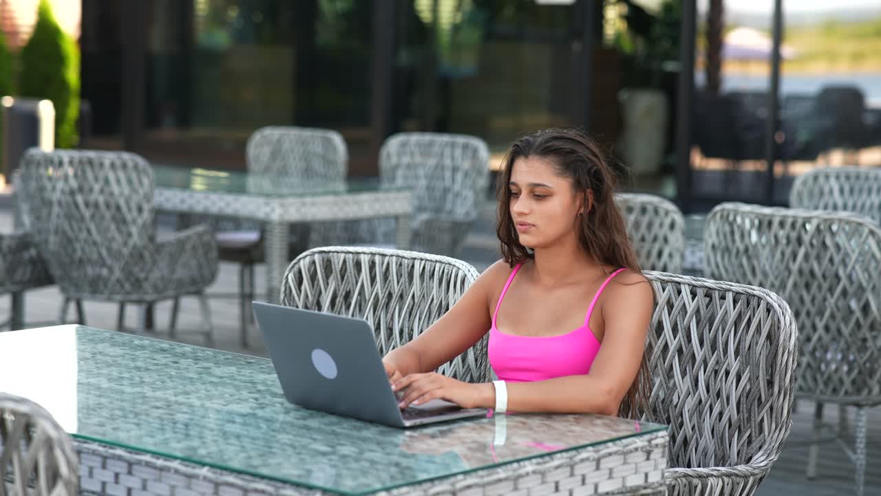 mujer trabajando en una computadora portátil en una terraza de café