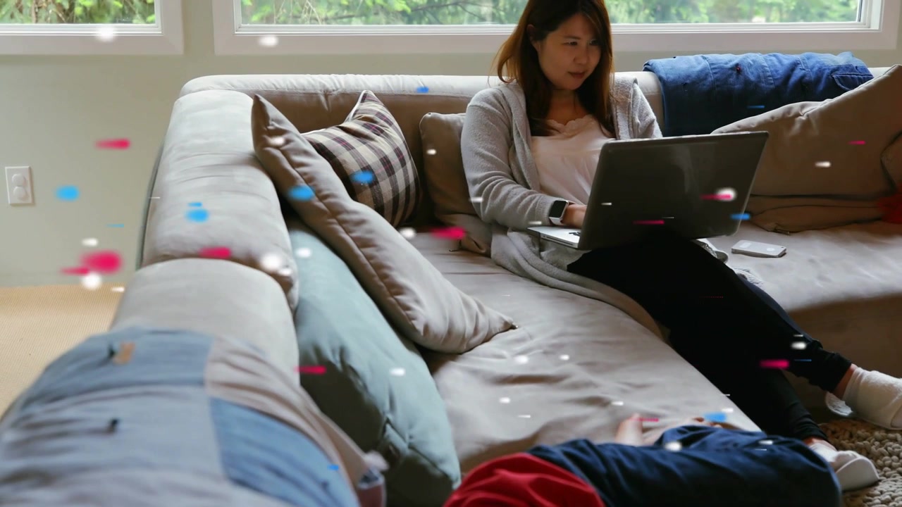 Woman typing on laptop while boy in red moving to see screen, tech particles highlighting laptop
