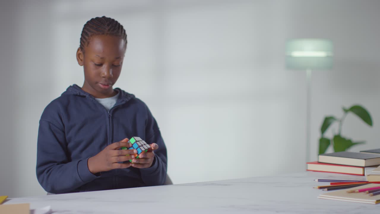 Boy On ASD Spectrum At Home Sitting At Table Solving Puzzle Cube