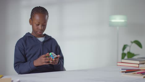 boy on asd spectrum at home sitting at table solving puzzle cube