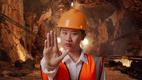 close up of asian female engineer with safety helmet disapproving with no hand sign in underground mine tunnel