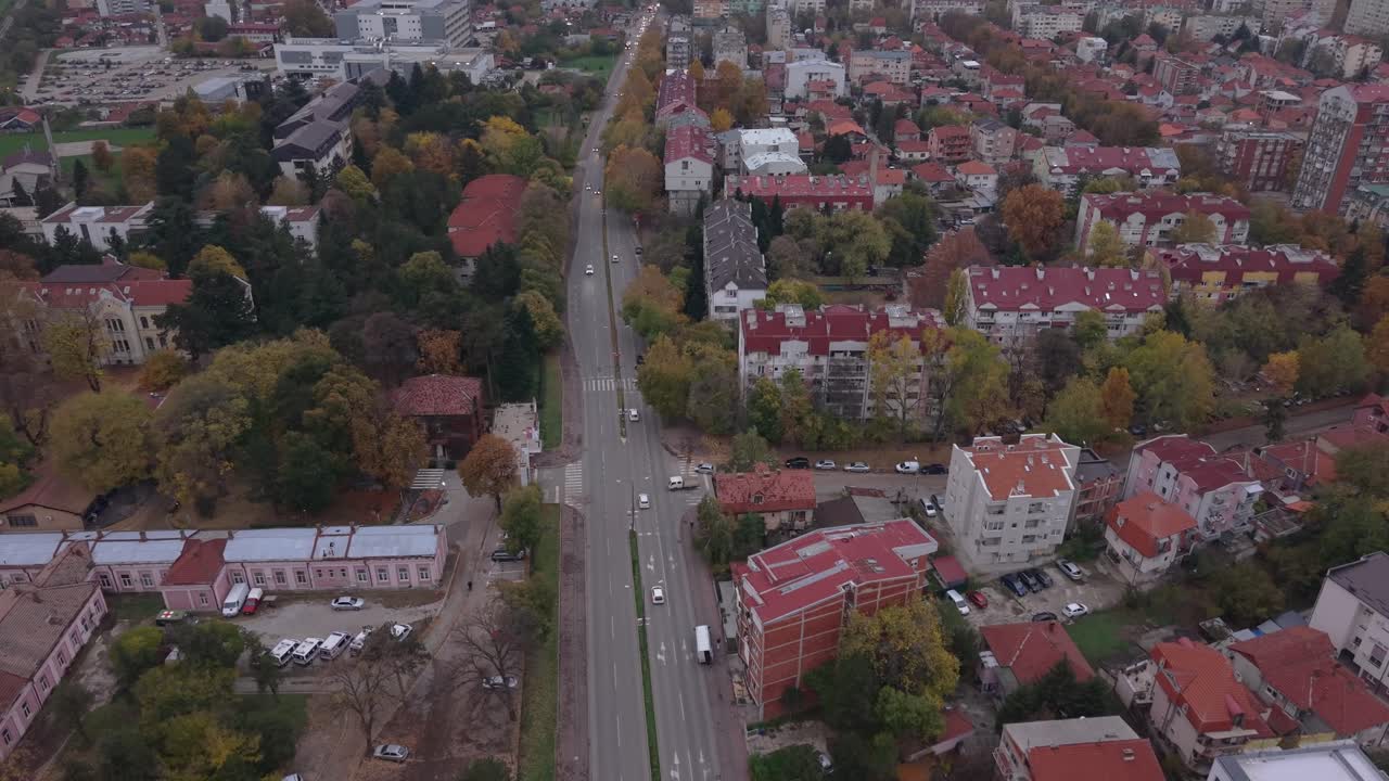 Dron sleduje auto po bulváru v Niši a naklání se nahoru, aby v dynamickém leteckém záběru odhalil okolní panorama města a městské prostředí