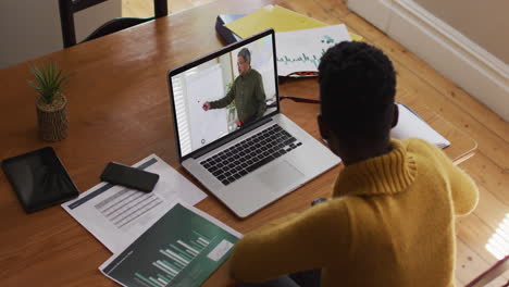 estudiante afroamericana usando una computadora portátil en una videollamada con un profesor masculino
