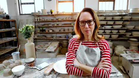 Female-potter-standing-with-arms-crossed-in-pottery-workshop-4k