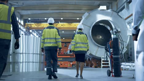 siguiente disparo de ingenieros y trabajadores de la industria pesada caminando a través de la fábrica de fabricación de tubos. instalación moderna para el diseño y construcción de oleoductos de transporte de petróleo, gas y combustibles. ángulo bajo