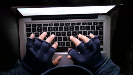 person using a laptop with gloves