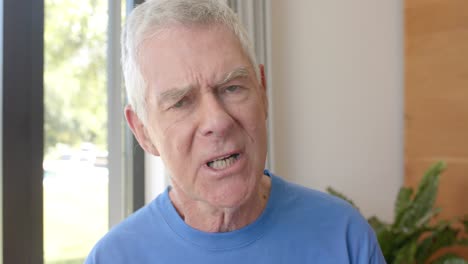 portrait of serious senior caucasian man making video call at home, unaltered, in slow motion