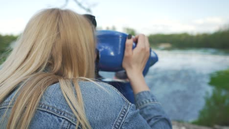 mujer joven no identificable mira los binoculares del telescopio en la cascada de ventas rumba