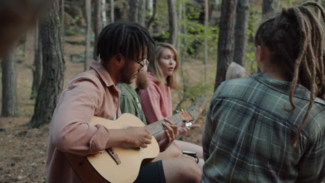 friends playing guitar in the forest