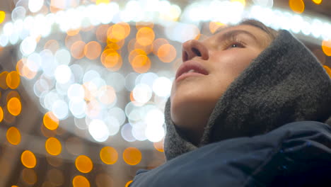 woman looking up at night lights