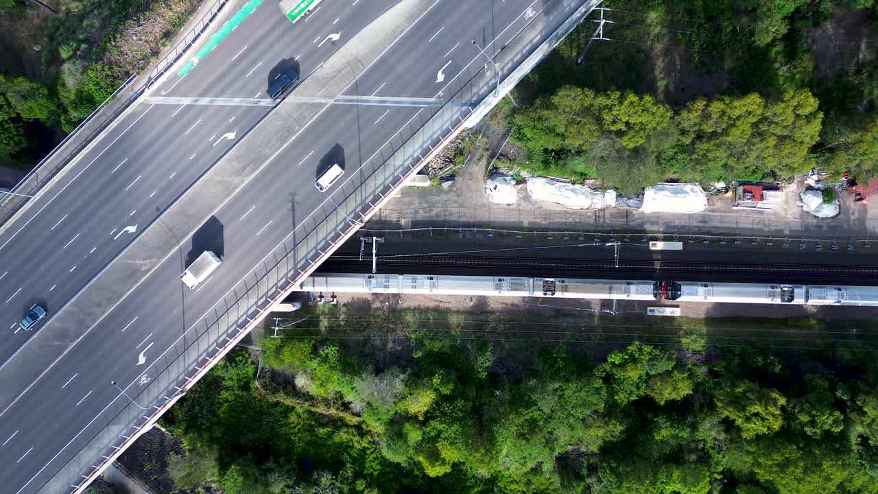 Drone aerial landscape of car commute vehicles traffic transport over Tuggerah with carriage on train line bridge railway tracks suburbs of Central Coast Australia urban infrastructure neighbourhood