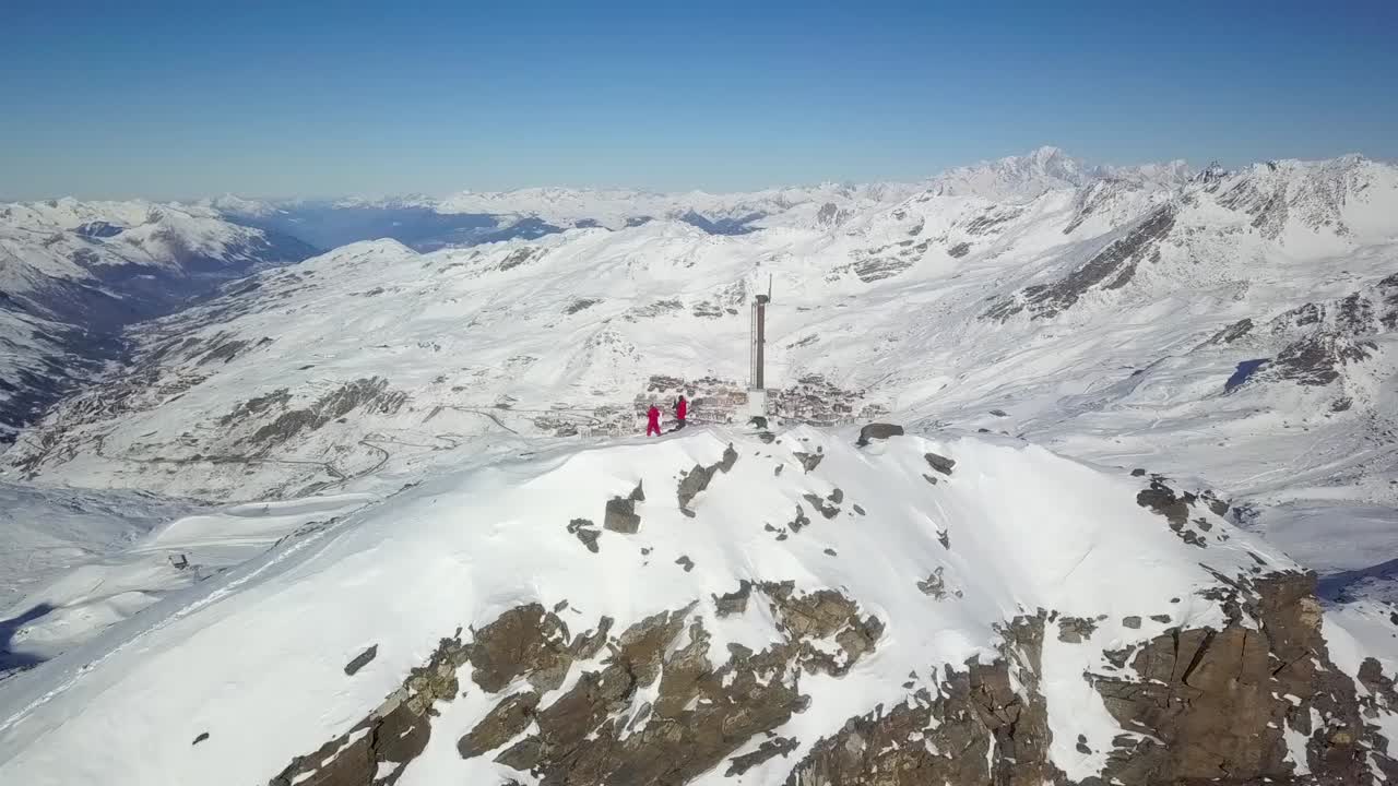 Swashbuckling Skiers on top of Mountain Peak in Val Thorens, French Alps - Aerial Orbit ascending 360 shot