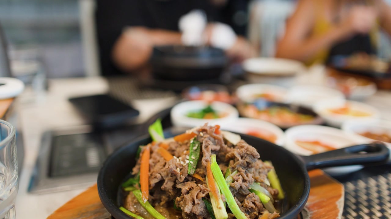 Close-up shot of steaming beef bulgogi with vegetables served in a hot cast iron skillet