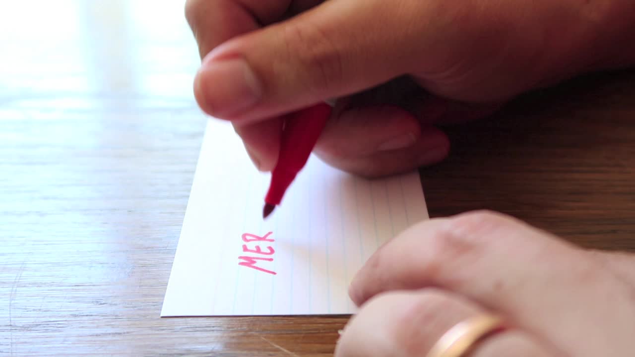 남성 손이 작은 종이 카드에 영구 마커 펜을 사용하여 메모를 작성하면서 영상을 닫습니다.