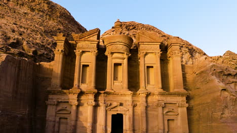 ad deir monastery in ancient city of petra, jordan during sunset - aerial pullback