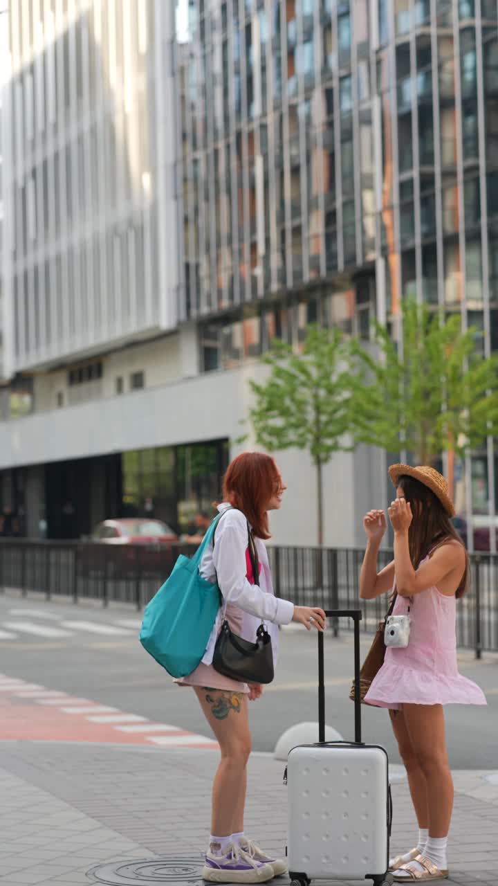 dos amigos hablando y esperando con equipaje en una calle de la ciudad