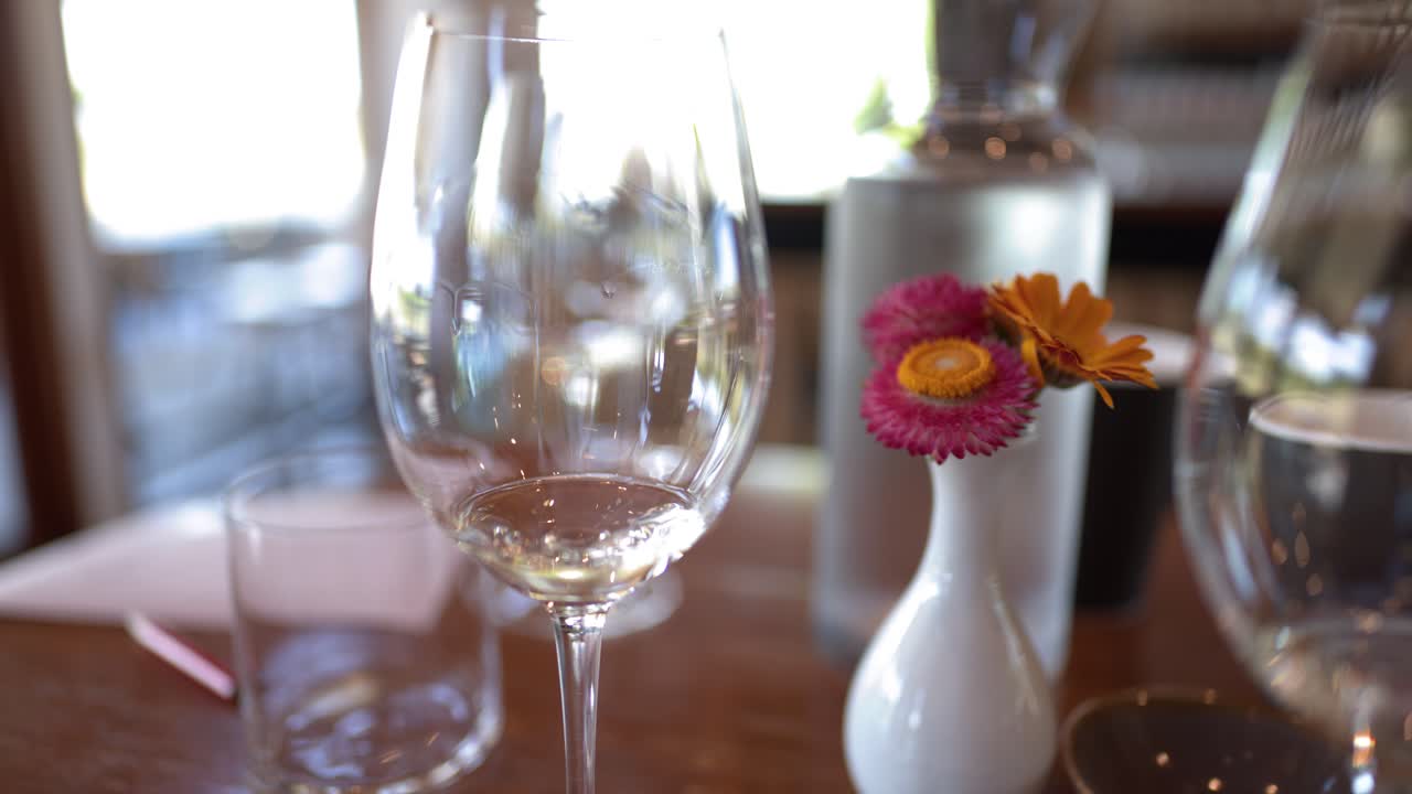 Nærbillede af et hvidvinsglas på et bord med blød bokeh-belysning