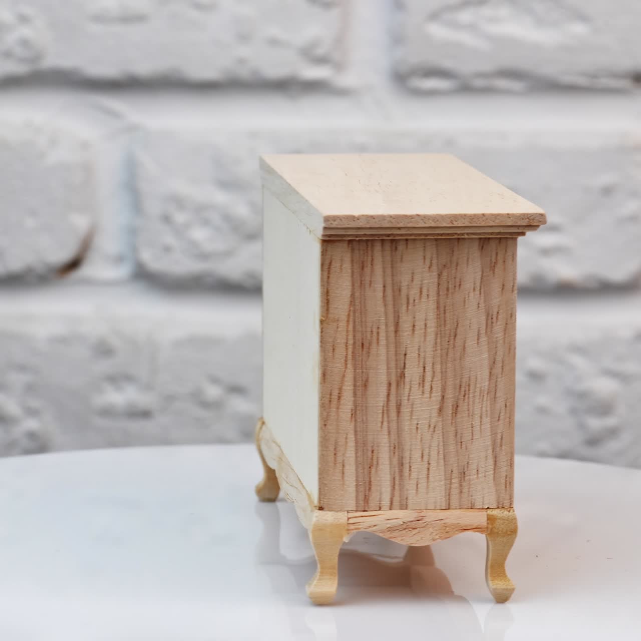 Nice little chest of drawers made from wood. Toy furniture on the rotating table. White backdrop