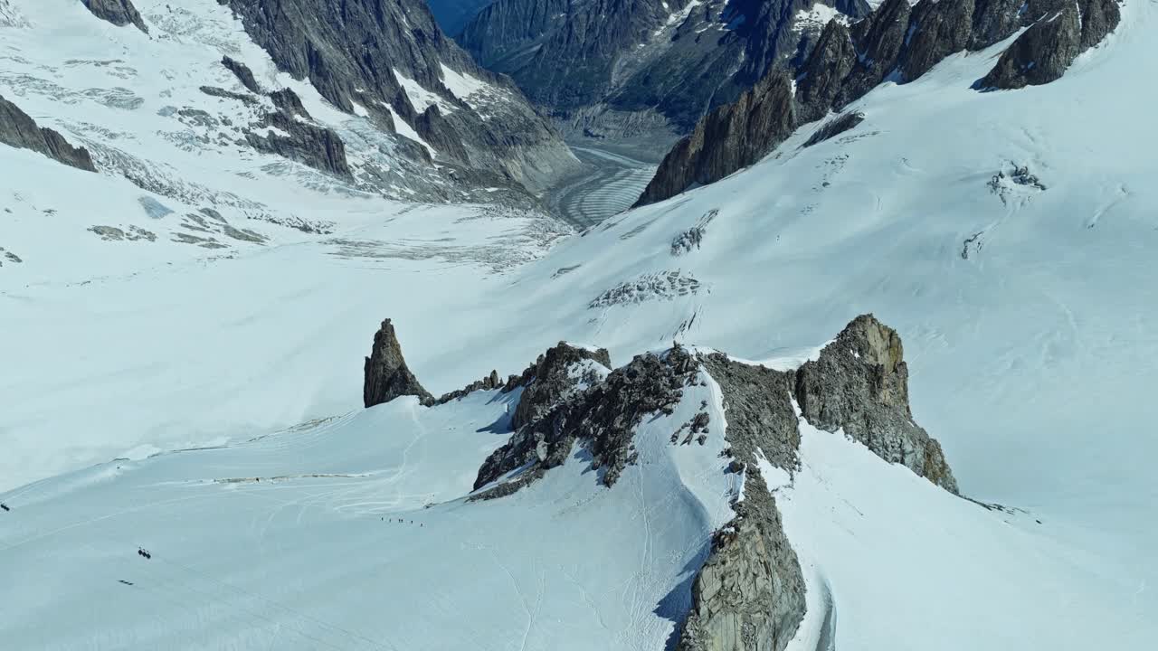 Una ripresa aerea con dolly e tilt up sul vasto paesaggio innevato delle Alpi francesi vicino a Chamonix, che cattura la bellezza aspra delle cime ad alta quota e delle profonde valli glaciali.