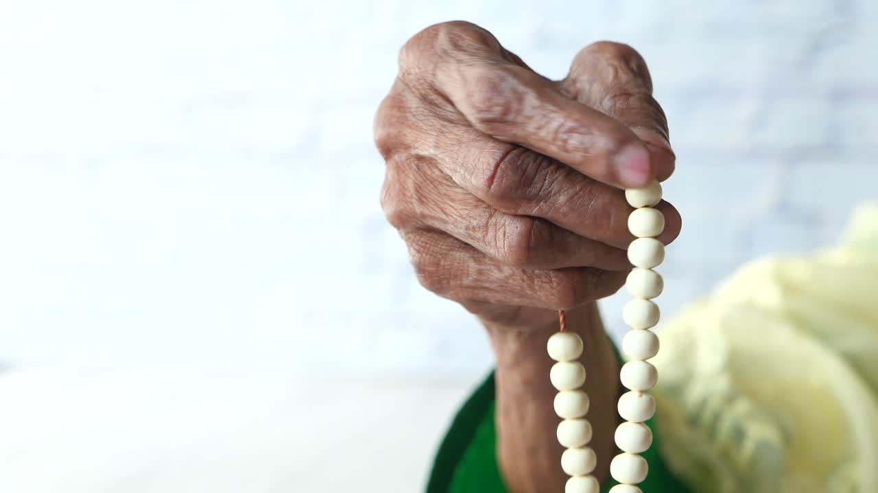 mano de anciano con cuentas de oración