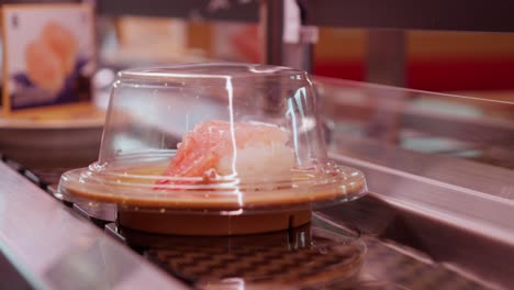 Pieces-of-shrimp-sushi-arrive-on-conveyor-belt-in-restaurant,-close-up