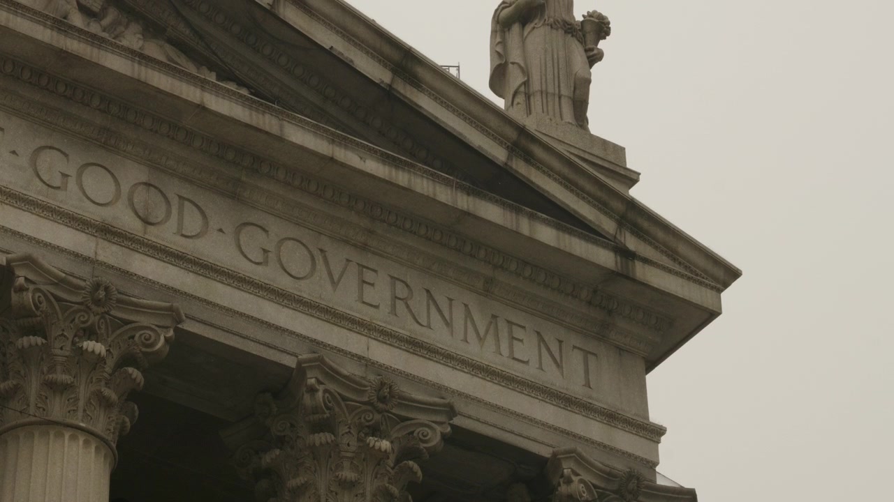 Ripresa inclinata al rallentatore della facciata di un tribunale degli Stati Uniti con la sola scritta "Good Government" in una giornata nuvolosa