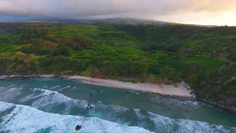 flying-forward-decending-toward-a-beach-on-the-coast-of-Maui-Hawaii-at-sunset-on-a-cloudy-day,-dolly-forward-down