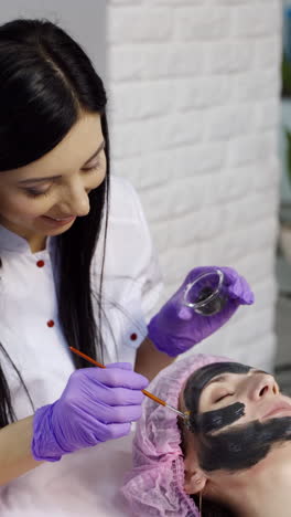cleansing face mask. woman receiving cosmetic procedure in beauty salon. vertical video