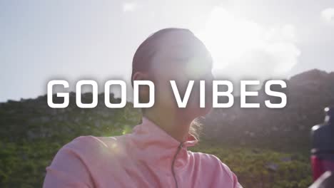 animation of the words good vibes written in white over woman exercising in mountains drinking water