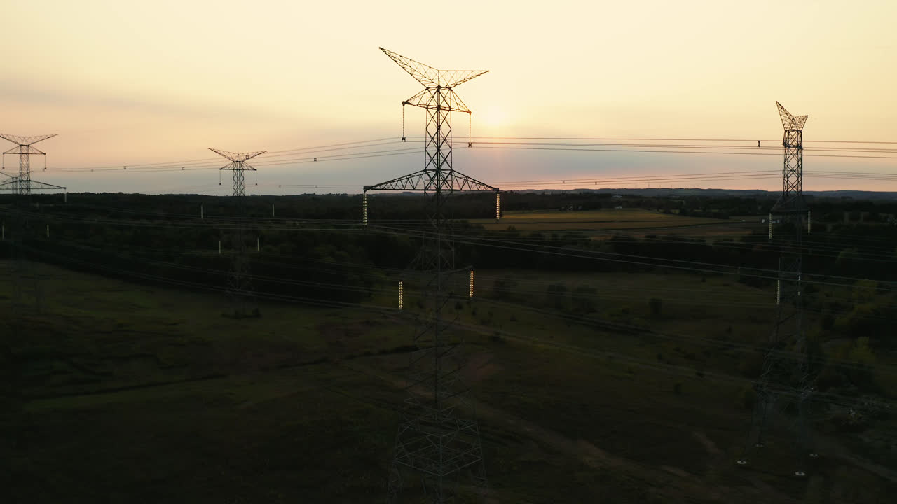 Aerial Drone Flyover of High Voltage Transmission Power Lines Silhouette in Rural Countryside