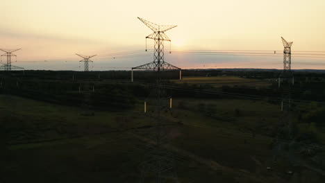 aerial drone flyover of high voltage transmission power lines silhouette in rural countryside