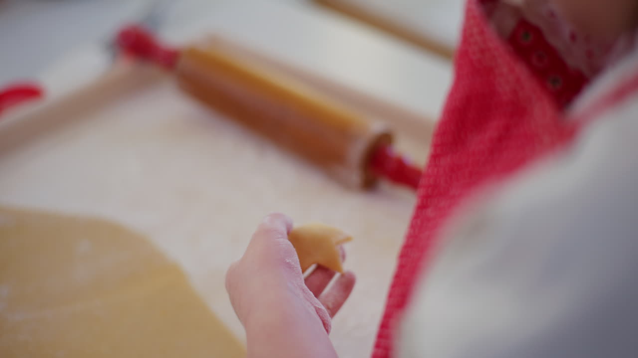 한 소년이 베이킹 캔에서 쿠키를 잘라서 베이킹 트레이에 놓습니다.