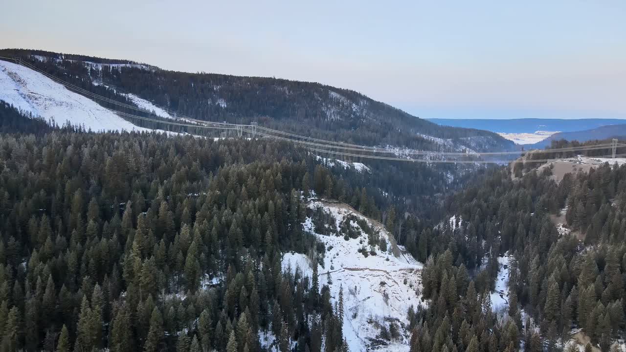 paisaje nevado y energía: vista aérea de líneas de transmisión de alto voltaje y pilones en columbia británica, canadá