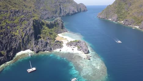 4k aerial drone view of beautiful private island in the philippines with tour boat in distance star beach el nido, palawan