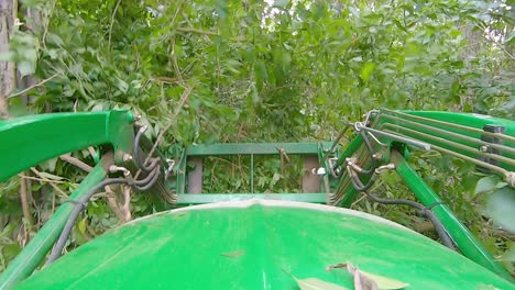 pov of equipment operator using a loader with forks to move debris and brush in a yard surrounded by the woods