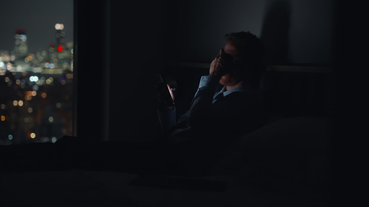 Uomo d'affari stanco che invia messaggi a letto.