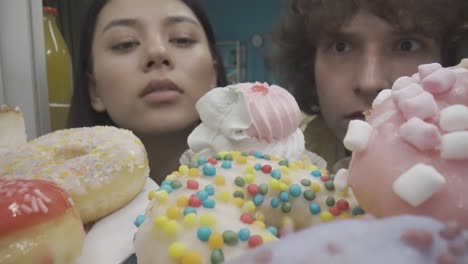 couple gazing at delicious donuts in a refrigerator