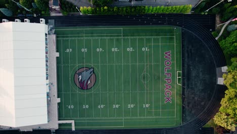 Aerial-top-view-ascend:-White-Event-Tent-on-Green-Football-Field,-Chicago-USA