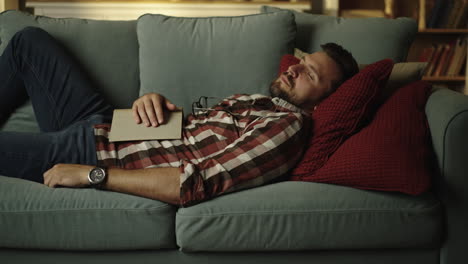 man sleeping on a couch with a book