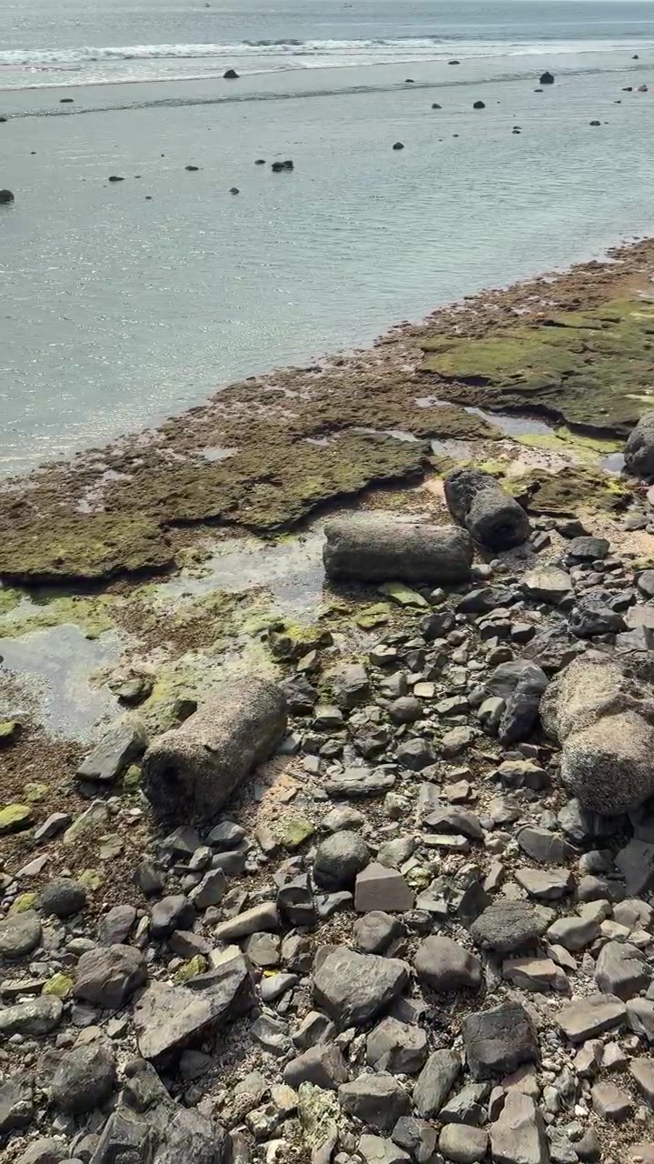 Costa rocciosa con pietre muschiose e dolci onde dell'oceano