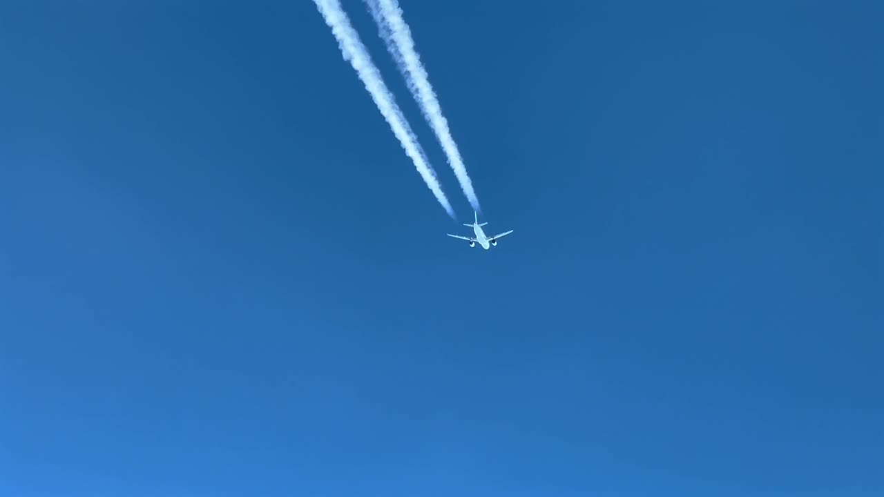 пилот белого реактивного самолета, перелетающего слева направо через голубое небо, с видимым контралом