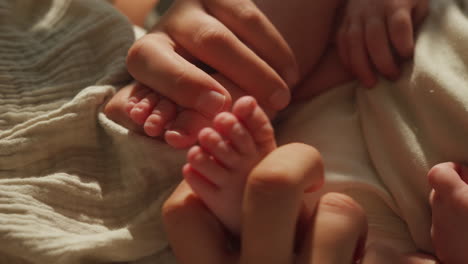 a close-up shot of a newborn’s tiny feet being cradled by an adult’s hand, set against a soft blanket