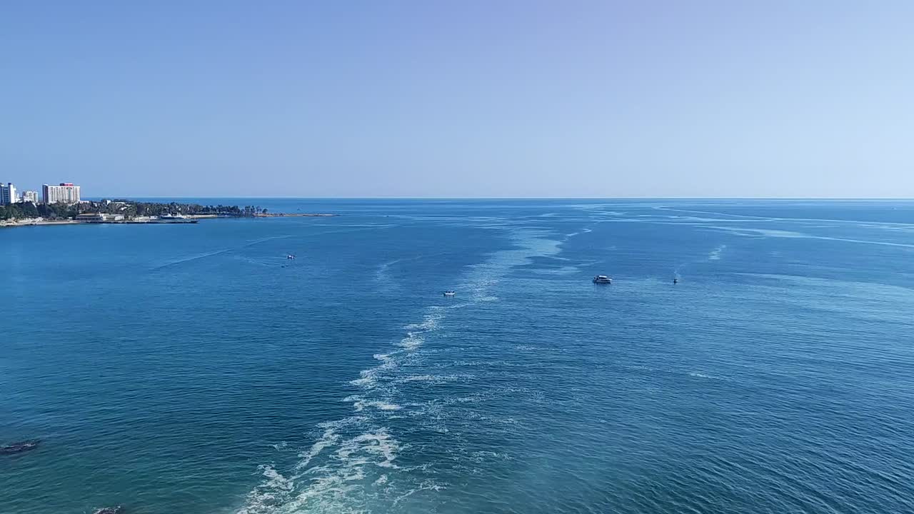 Aerial footage capturing expansive ocean view near Antalya Bay, Turkey. Features boat trails over the deep blue sea with scenic coastline in the distance on a clear, sunny day