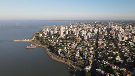 Aerial-view-of-the-coastal-city-of-Posadas-Misiones-Argentina,-drone-shot-of-densely-populated-coastal-city-cloudy-sky