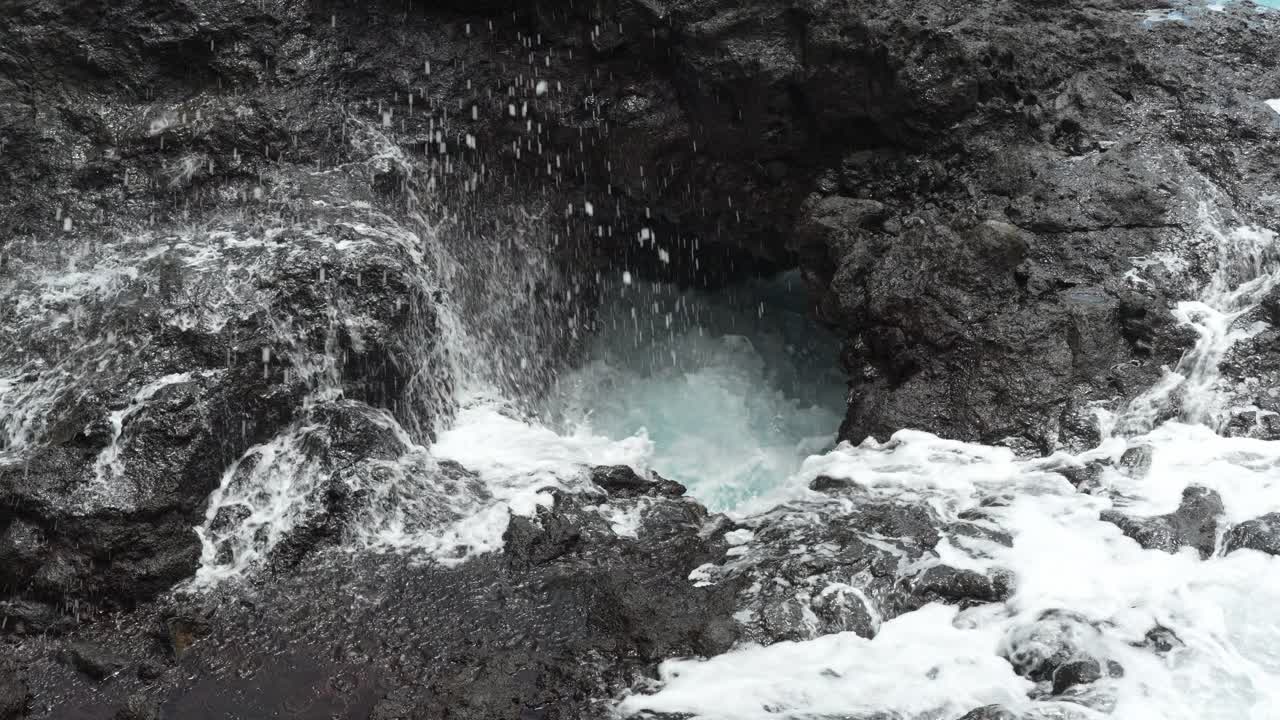 poderosas olas del océano golpeando agujero en el acantilado rocoso haciendo salpicaduras, vista estática
