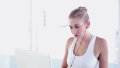 Sportliche-Blondine-Benutzt-Laptop-Und-Hört-Musik