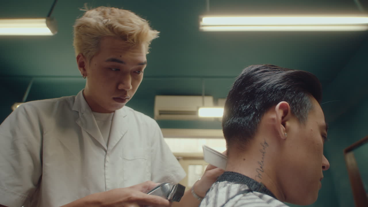 Asian Barber Working with Hair Clippers and Comb at the Barbershop