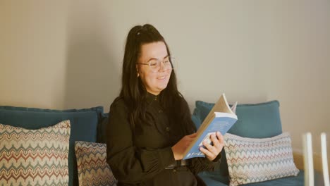 mujer feliz leyendo un libro en el sofá en la sala de estar - de cerca